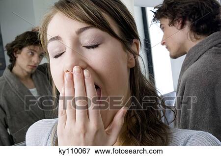 Portrait of a woman yawning, man in bathrobe in front of bathroom mirror in background View Large Photo Image Stock Photo - Portrait of a woman yawning, man in bathrobe in front of bathroom mirror in background. Fotosearch