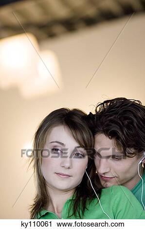Portrait of a young couple with earphones embracing View Large Photo Image Stock Image - Portrait of a young couple with earphones embracing. Fotosearch