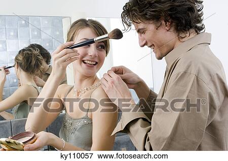 Smiling couple in the bathroom, woman holding make-up brush, man fastening her necklace View Large Photo Image Stock Photo - Smiling couple in the bathroom, woman holding make-up brush, man fastening her necklace. Fotosearch