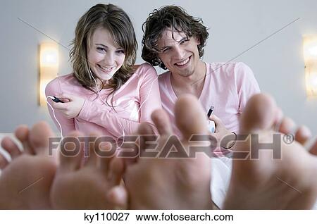 Smiling couple sitting, barefoot in foreground View Large Photo Image Stock Photo - Smiling couple sitting, barefoot in foreground. Fotosearch