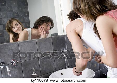 Woman embracing man looking in bathroom mirror View Large Photo Image Stock Photo - Woman embracing man looking in bathroom mirror. Fotosearch