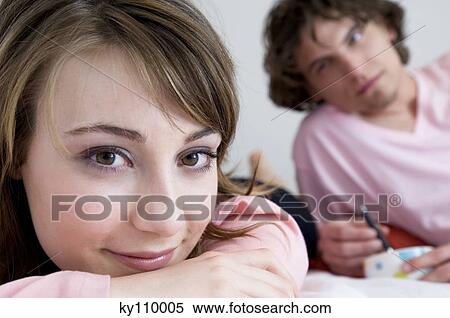 Woman looking at the camera, man lying on bed in background View Large Photo Image Stock Photography - Woman looking at the camera, man lying on bed in background. Fotosearch