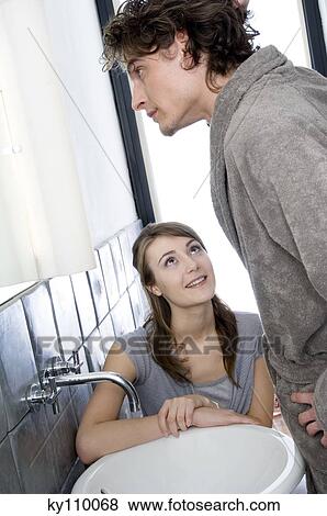 Woman sitting, looking at man in bathrobe standing in front of bathroom mirror View Large Photo Image Stock Photo - Woman sitting, looking at man in bathrobe standing in front of bathroom mirror. Fotosearch
