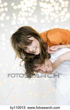 Young man carrying woman on his back, smiling for the camera View Large Photo Image Stock Image - Young man carrying woman on his back, smiling for the camera. Fotosearch
