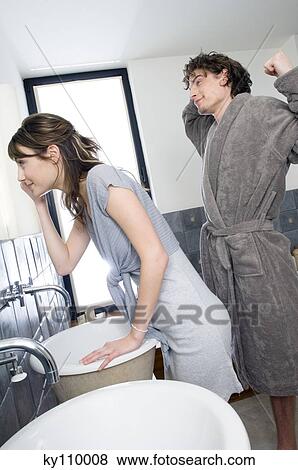 Young woman looking in bathroom mirror, man in bathrobe streching View Large Photo Image Stock Photo - Young woman looking in bathroom mirror, man in bathrobe streching. Fotosearch