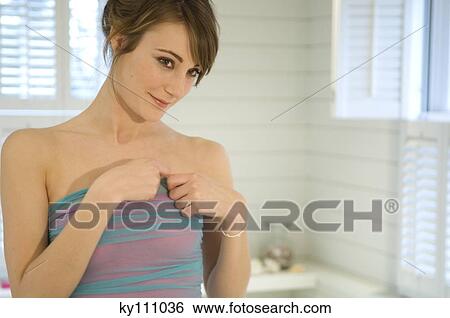 Stock Photograph - Portrait of a young woman getting dressed in bathroom. Fotosearch