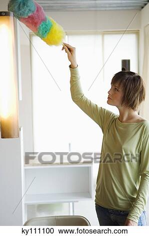 Woman dusting a lamp with a feather duster View Large Photo Image Stock Image - Woman dusting a lamp with a feather duster. Fotosearch