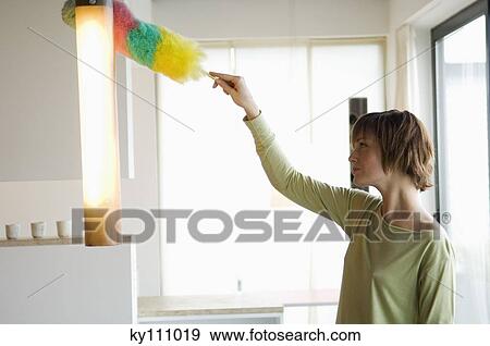 Woman dusting a lamp with a feather duster View Large Photo Image Stock Photo - Woman dusting a lamp with a feather duster. Fotosearch
