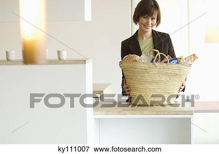 Young smiling woman with shopping basket in the kitchen View Large Photo Image Stock Photo - Young smiling woman with shopping basket in the kitchen. Fotosearch
