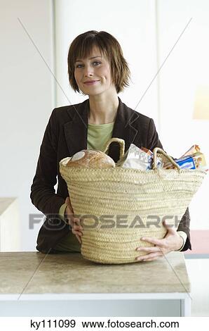 Young smiling woman with shopping basket in the kitchen View Large Photo Image Stock Photo - Young smiling woman with shopping basket in the kitchen. Fotosearch
