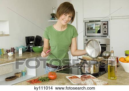 Young woman cooking, smiling for the camera View Large Photo Image Picture - Young woman cooking, smiling for the camera. Fotosearch