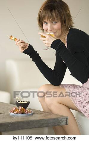 Young woman having aperitive in living-room, looking at the camera View Large Photo Image Stock Photography - Young woman having aperitive in living-room, looking at the camera. Fotosearch