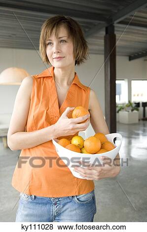 Young woman holding a bowl of oranges View Large Photo Image Stock Photo - Young woman holding a bowl of oranges. Fotosearch