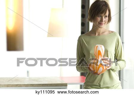 Young woman holding a vase View Large Photo Image Stock Photography - Young woman holding a vase. Fotosearch