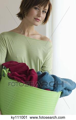 Stock Image - Young woman holding clothes basket. Fotosearch