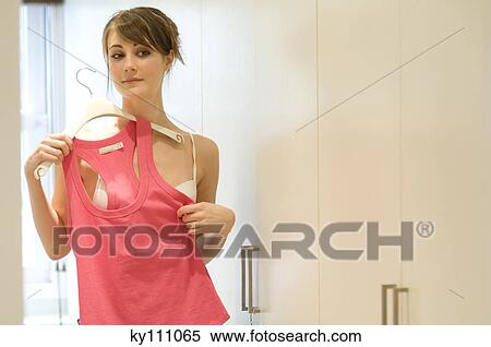 Young woman holding up pink tank top against herself View Large Photo Image Stock Photography - Young woman holding up pink tank top against herself. Fotosearch