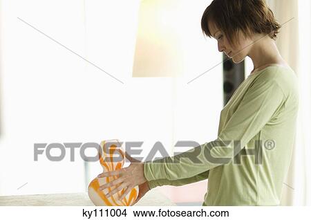 Young woman in profile, holding a vase View Large Photo Image Picture - Young woman in profile, holding a vase. Fotosearch