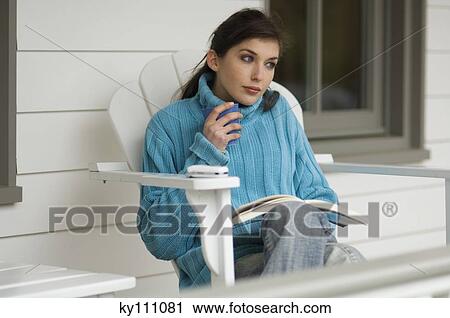 Young woman reading, sitting on a chair, outdoors View Large Photo Image Stock Image - Young woman reading, sitting on a chair, outdoors. Fotosearch