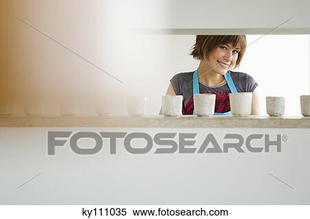 Young woman smiling for the camera in kitchen View Large Photo Image Stock Photography - Young woman smiling for the camera in kitchen. Fotosearch