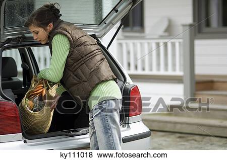 Young woman taking a shopping basket out of a car trunk View Large Photo Image Stock Photo - Young woman taking a shopping basket out of a car trunk. Fotosearch