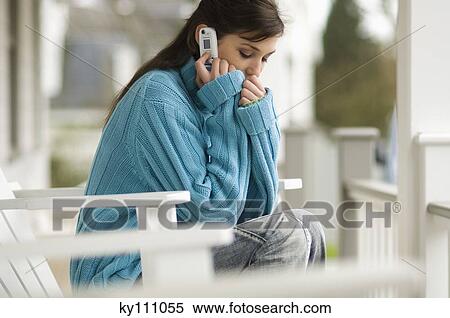 Young woman using mobile phone, sitting on a chair, outdoors View Large Photo Image Stock Photography - Young woman using mobile phone, sitting on a chair, outdoors. Fotosearch