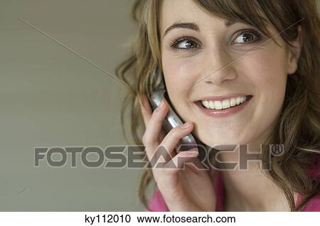 Portrait of a young smiling woman using mobile phone View Large Photo Image Stock Image - Portrait of a young smiling woman using mobile phone. Fotosearch