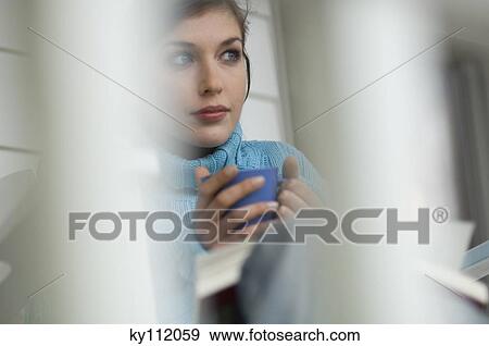Stock Photo - Young thinking woman holding cup. Fotosearch