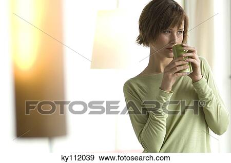 Young woman holding a cup View Large Photo Image Stock Photo - Young woman holding a cup. Fotosearch