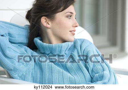 Picture - Young woman in blue pullover, looking away, outdoors. Fotosearch