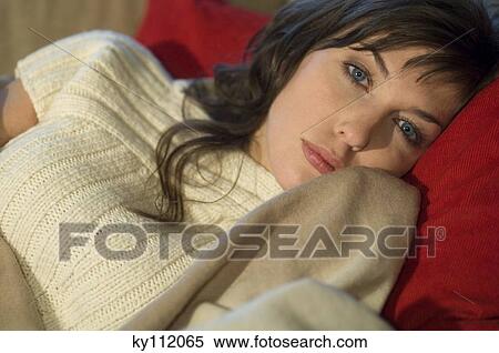 Young woman lying on a sofa, looking at the camera, close-up View Large Photo Image Stock Photography - Young woman lying on a sofa, looking at the camera, close-up. Fotosearch