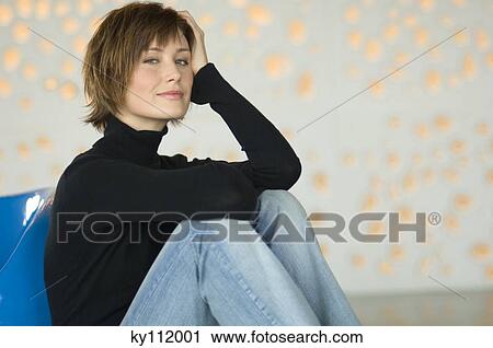 Young woman sitting on the floor, looking at the camera View Large Photo Image Stock Image - Young woman sitting on the floor, looking at the camera. Fotosearch