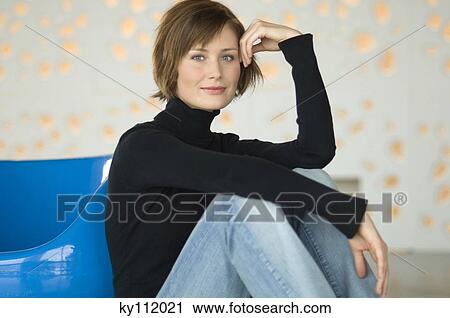 Young woman sitting on the floor, looking at the camera View Large Photo Image Stock Image - Young woman sitting on the floor, looking at the camera. Fotosearch