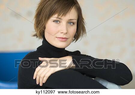 Stock Photo - Young woman sitting on the floor, looking at the camera. Fotosearch
