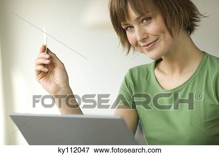 Stock Photo - Young woman using laptop computer, smiling for the camera. Fotosearch