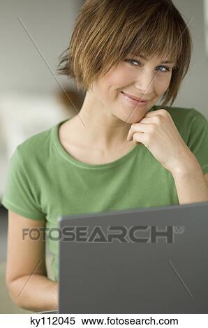 Young woman using laptop computer, smiling for the camera View Large Photo Image Stock Photography - Young woman using laptop computer, smiling for the camera. Fotosearch
