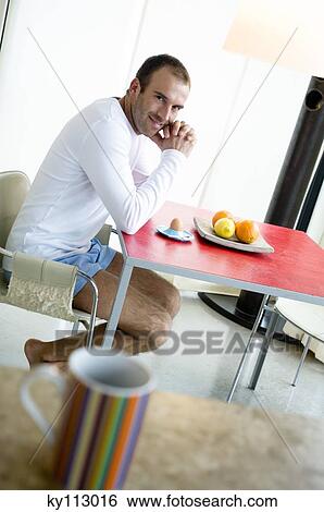 Man at breakfast table, looking at the camera, cup in foreground View Large Photo Image Stock Photograph - Man at breakfast table, looking at the camera, cup in foreground. Fotosearch