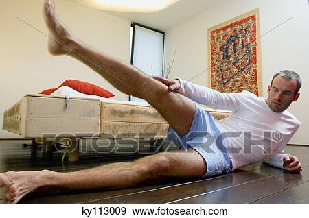 Man in bedroom, stretching, lying on the floor View Large Photo Image Stock Photo - Man in bedroom, stretching, lying on the floor. Fotosearch
