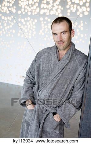 Picture - Man in grey bathrobe, leaning against wall, looking at the camera. Fotosearch