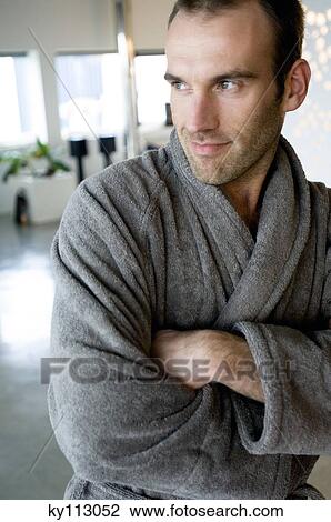 Stock Image - Man in grey bathrobe, leaning against wall, with crossed arms. Fotosearch
