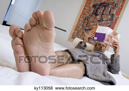Man in grey bathrobe, lying in bed, reading a book View Large Photo Image Stock Photo - Man in grey bathrobe, lying in bed, reading a book. Fotosearch