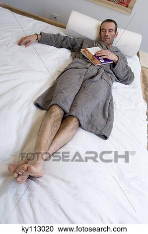 Stock Image - Man in grey bathrobe, sleeping in bed. Fotosearch