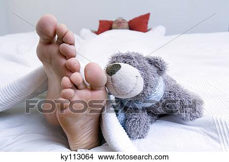 Man sleeping in bed, barefoot and teddy bear in foreground View Large Photo Image Picture - Man sleeping in bed, barefoot and teddy bear in foreground. Fotosearch