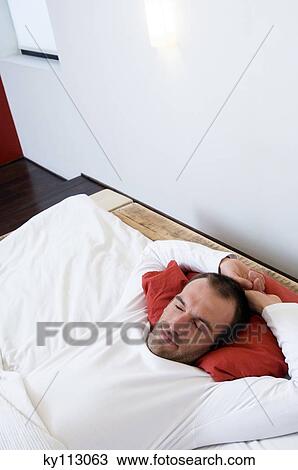 Stock Image - Man stretching in bed. Fotosearch