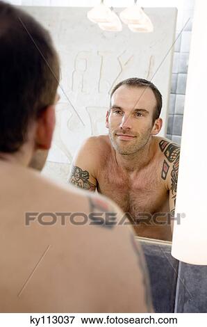 Tattooed man, barechested, looking in bathroom mirror View Large Photo Image Stock Photo - Tattooed man, barechested, looking in bathroom mirror. Fotosearch