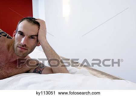 Tattooed man, barechested, lying in bed, looking at the camera View Large Photo Image Stock Image - Tattooed man, barechested, lying in bed, looking at the camera. Fotosearch