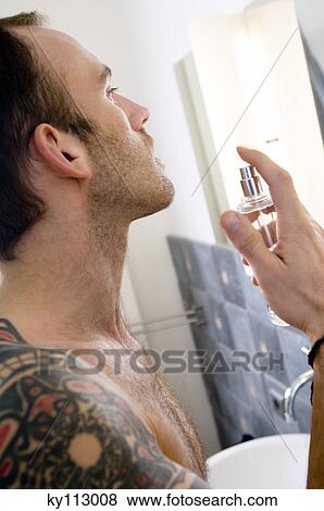 Tattooed man, barechested, spraying perfume in bathroom View Large Photo Image Stock Photo - Tattooed man, barechested, spraying perfume in bathroom. Fotosearch