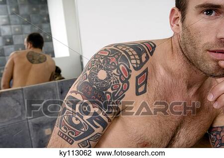 Tattooed man, barechested, standing in the bathroom, looking at the camera View Large Photo Image Stock Image - Tattooed man, barechested, standing in the bathroom, looking at the camera. Fotosearch