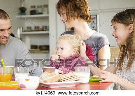 Stock Photo - Couple and 2 children at breakfast table. Fotosearch