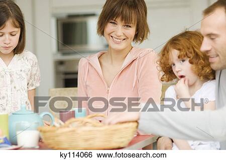 Stock Photograph - Couple and 2 little girls at breakfast table. Fotosearch