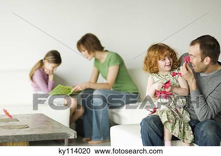 Couple and 2 little girls sitting in the living-room View Large Photo Image Stock Image - Couple and 2 little girls sitting in the living-room. Fotosearch